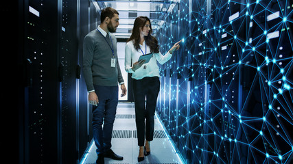 Female and Male IT Engineers Discussing Technical Details in a Working Data Center/ Server Room with Internet Connection Visualisation. - obrazy, fototapety, plakaty