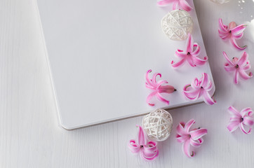 notepad on white wooden background. Pink hyacinth flowers on the table.