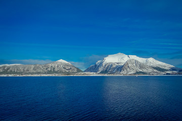 Amazing landscape of coastal scenes of huge mountain covered with snow on Hurtigruten during voyage in a blue sky