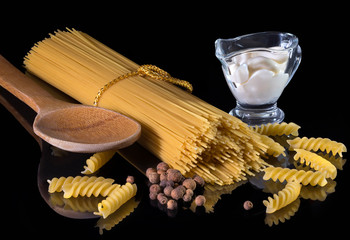 Yellow Italian pasta, spaghetti, black pepper isolated against the black isolated background. A beautiful still life. A close-up.
