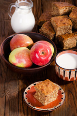 Walnut pie with apples in a bowl and milk, rustic breakfast.