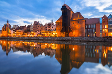 Historic port crane in Gdansk reflected in Motlawa river at dusk, Poland