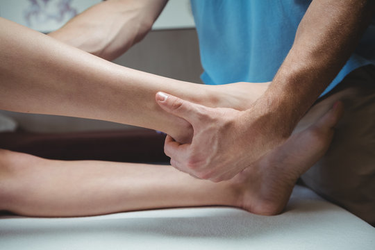 Physiotherapist giving physical therapy to the leg of a female patient