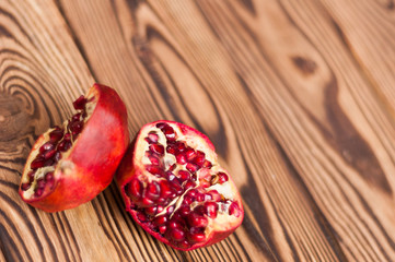 Two half red fresh ripe pomegranate with seeds on old brown weathered wooden planks