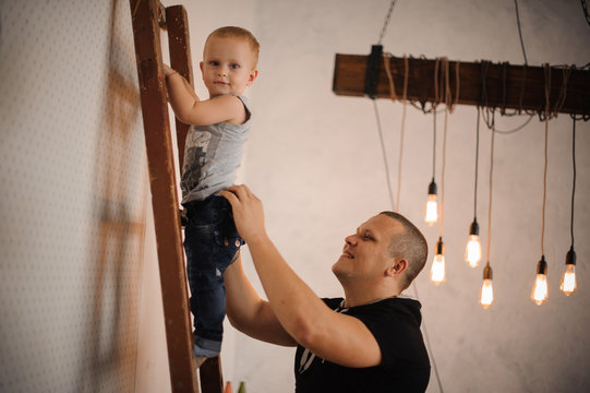 Father At Home Helping His Little Son Climbing Up The Ladder