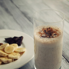 Banana chocolate smoothie with a dash of cinnamon. A glass of milk smoothie sprinkled with chocolate. Healthy breakfast. Lacto vegetarian dish. Toned photo.