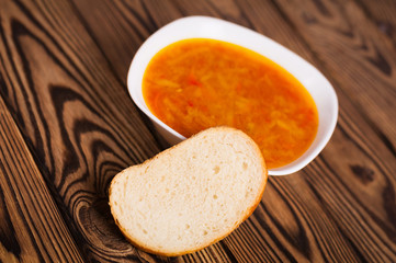 One full plate of fresh hot vegetable borscht and piece of bread on old weathered rustic wooden table. Ukrainian national food
