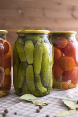 Pickled cucumbers and tomatoes in a glass jar on the table.