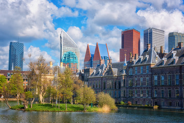 Binnenhof castle (Dutch Parliament) background with the Hofvijver lake against a background of skyscrapers and blue cloudy sky, Hague (Den Haag), Netherlands