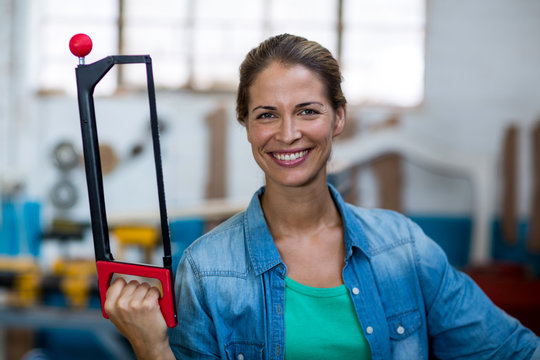 Happy female carpenter holding coping saw
