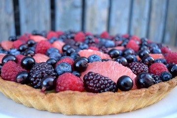Close up Fruit Tart Dessert Homebaked Fresh Raspberry Blueberry Grapefruit Summer Berries. Homemade Cake. Top view. Wooden Rustic Background