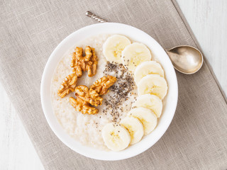 healthy breakfast - oatmeal with nuts, bananas, chia, top view, close up