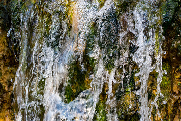 Quickly flowing mountain stream, close-up flowing water from the rock