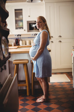 Portrait of pregnant woman standing in kitchen