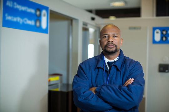 Airport security officer standing with arms crossed in airport terminal