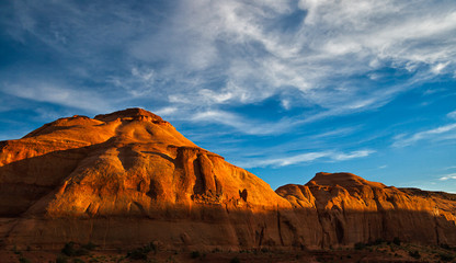 Fototapeta premium Beautiful landscape of sunlit sandstone red cliffs in the Monument Valley Navajo Tribal Park with a blue cloudy sky, Arizona.