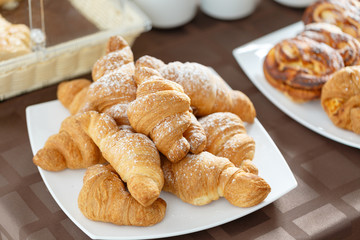 Fresh croissants on white plate. French traditional pastry. Breakfast in hotel smorgasbord.