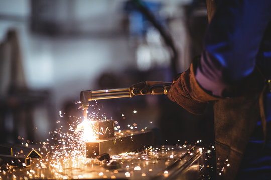 Mid-section of male welder working on a piece of metal