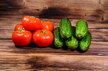 Ripe tomatoes and cucumbers on wooden table