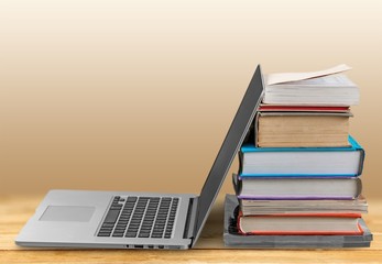 Stack of books with laptop on table