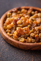 Raisins in wooden bowl on rusty background