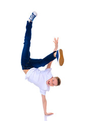 A cheerful little boy from school age is dancing breakdance.