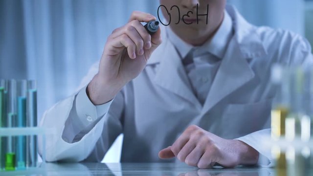 Scientist writing chemical formula on transparent board, pharmaceutical research