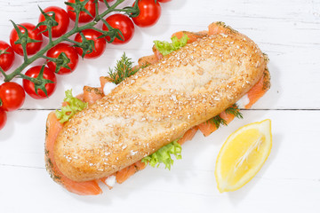 Sandwich Baguette Vollkorn Brötchen belegt mit Lachs Fisch von oben auf Holzbrett