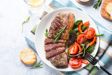 Grilled beef striploin steak with fresh salad. Top view.