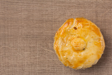 Stuffed chicken pie known as Empada in Portugal and Brazil. One snack on wood table, flat design.