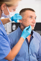 Female doctor is preparing patient for procedure with using marker