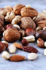 mixed nuts on grey background. Healthy food and snack. Walnut, pecan, almonds, hazelnuts and cashews.