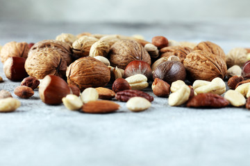 mixed nuts on grey background. Healthy food and snack. Walnut, pecan, almonds, hazelnuts and...
