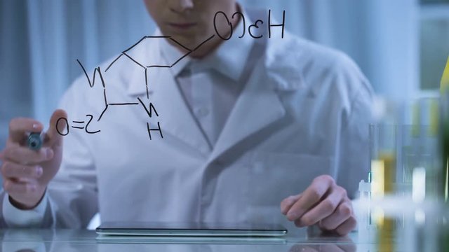 Chemist finishing formula on glass board, entering research result in tablet