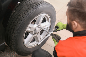 Professional mechanic changing tire in car service center