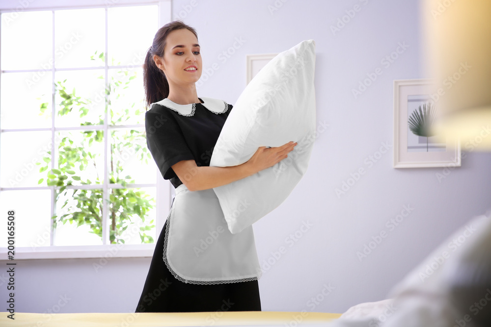 Poster Young maid making bed in hotel room