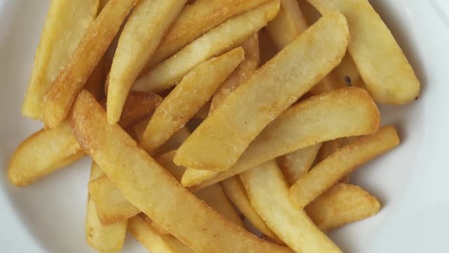 Top view closeup of delicious french fries in white plate - spinning shot