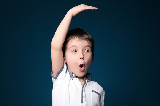 Little boy measuring height on color background