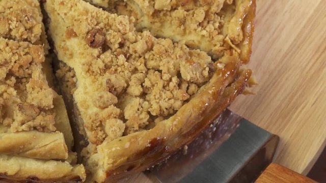 Closeup hand taking away slice of fresh baked apple pie isolated from wooden plate
