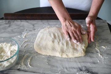 Hands kneading dough on marble board