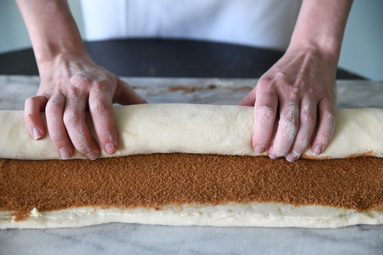 Hands rolling dough in cinnamon