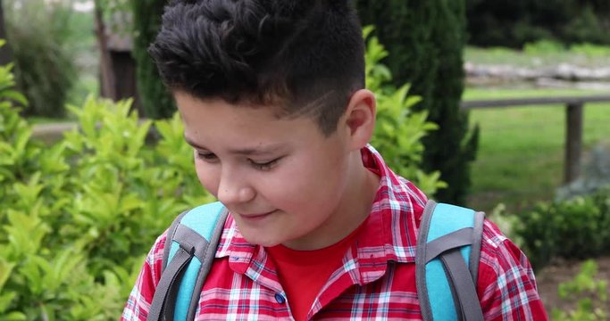 Portrait of a young handsome preteen boy with backpack looking at the map and walking at the camp area