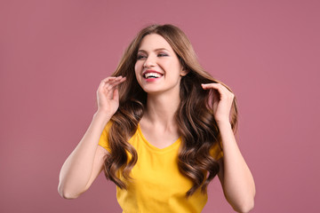 Portrait of young woman with long beautiful hair on color background