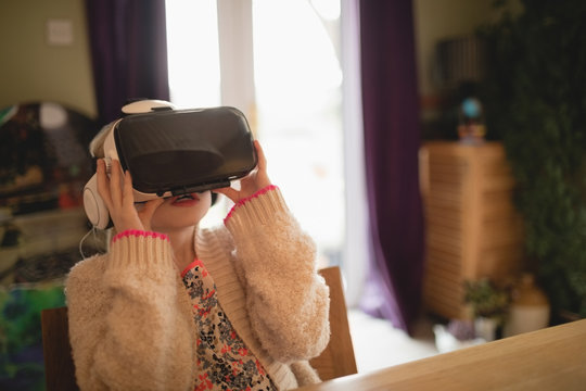 Girl sitting at table and using virtual realty headset