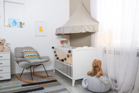 Cozy baby room interior with crib and rocking chair