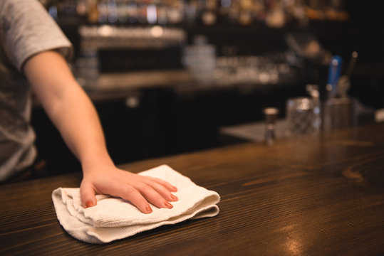 Bartender Cleaning Bar Counter Using A Rag