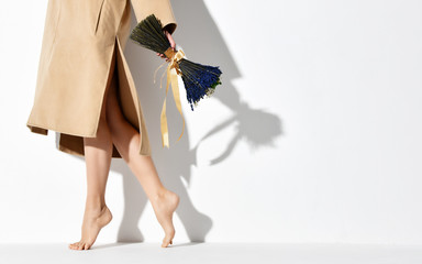 Beautiful female legs wearing brown yellow designers dress coat and bouquet of blue flowers lavender