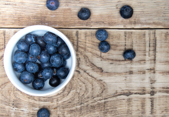 fresh bilberry berry in a white cup on a wooden table
