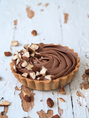 Top view of chocolate tarts served almond nuts on shabby white wooden background