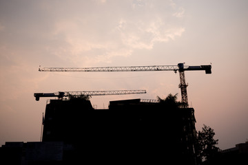 silhouette The construction of the building by using crane construction equipment transporter
